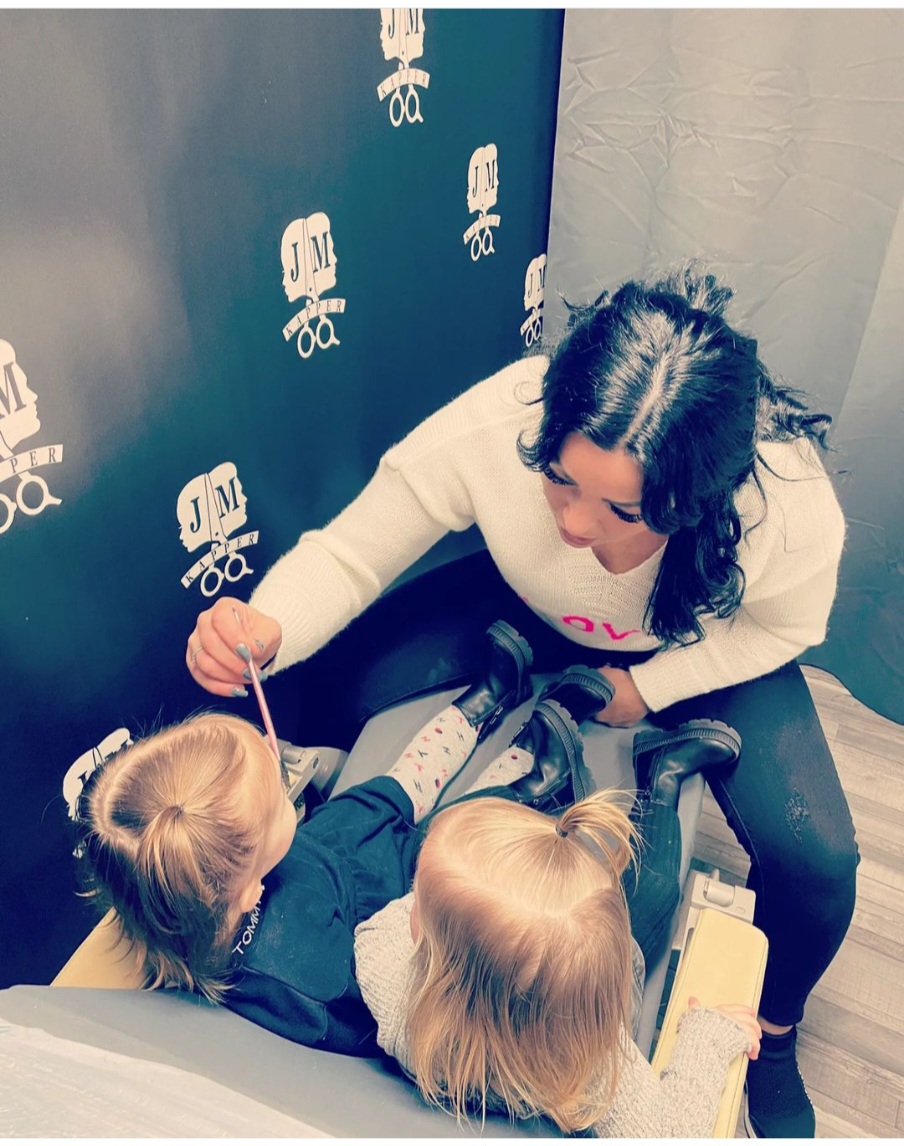 Jasmina knipt twee kleine kinderen voor de zwarte logowand