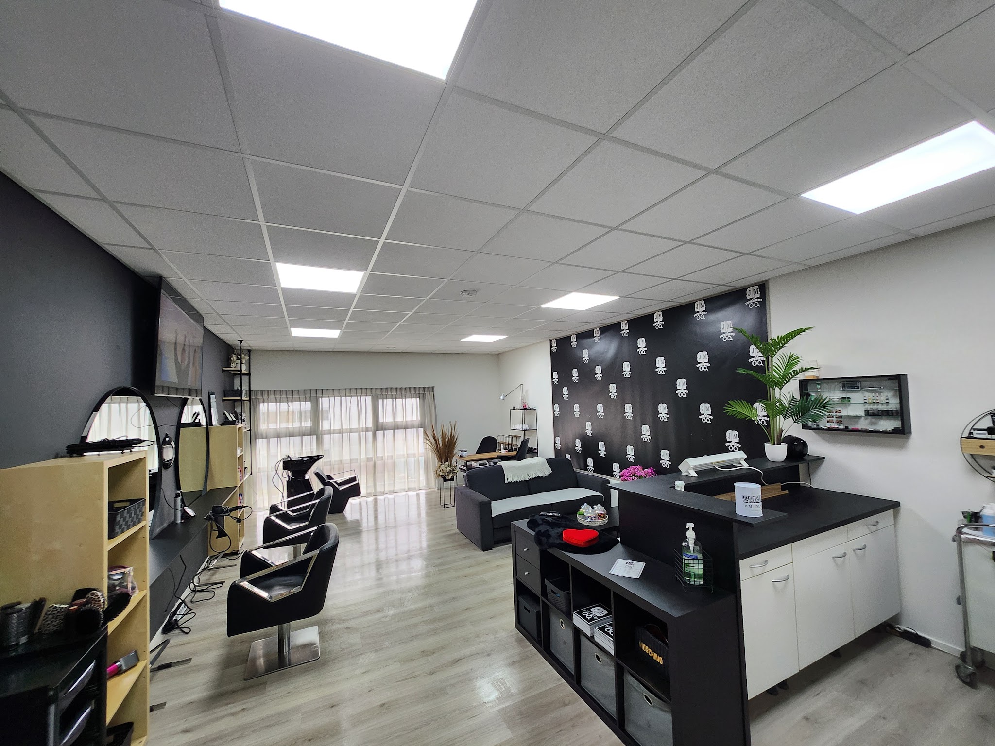 De salon van JM Kapper met kappersstoelen, spiegels en de zwarte wand met logo's
